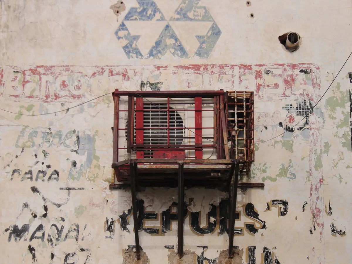 מזגן ישן בתוך סורג חלוד על קיר מתקלף